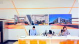 Office with wall of graphics behind people sitting at a desk