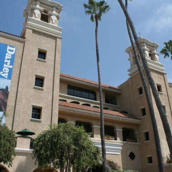 Large spanish style building with two blue hanging Darley signs with pictures of a horse