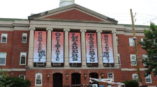 Committed Optimistic Leaders Transforming Society banners hanging at a building entrance