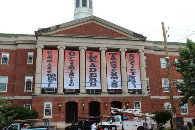 Committed Optimistic Leaders Transforming Society banners hanging at a building entrance