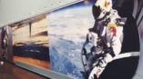 Wall mural of person in Red Bull suit and helmet flying above earth
